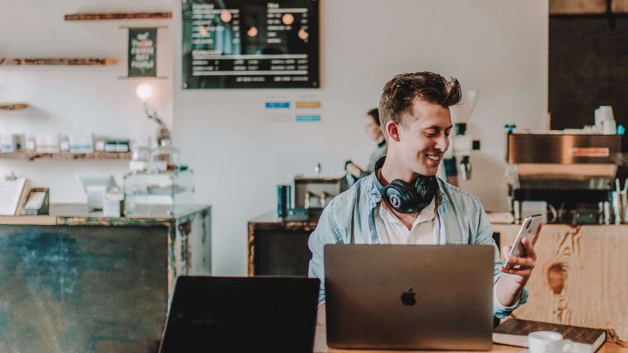 Man at coffee shop looking at an online bank to save his money